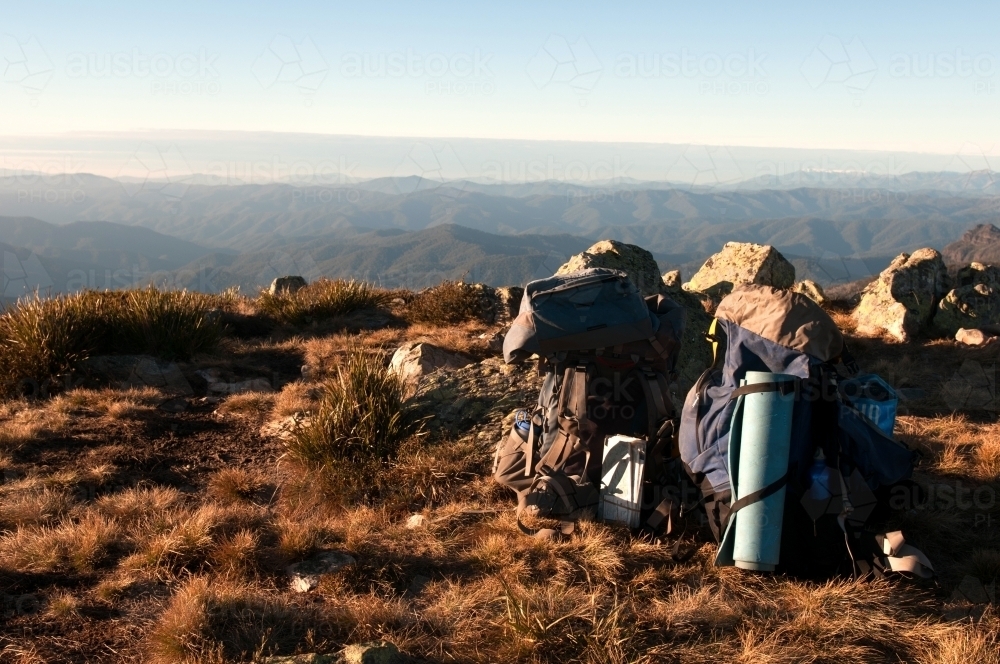 Hiking gear leaning against rocks with mountain range in the background. - Australian Stock Image
