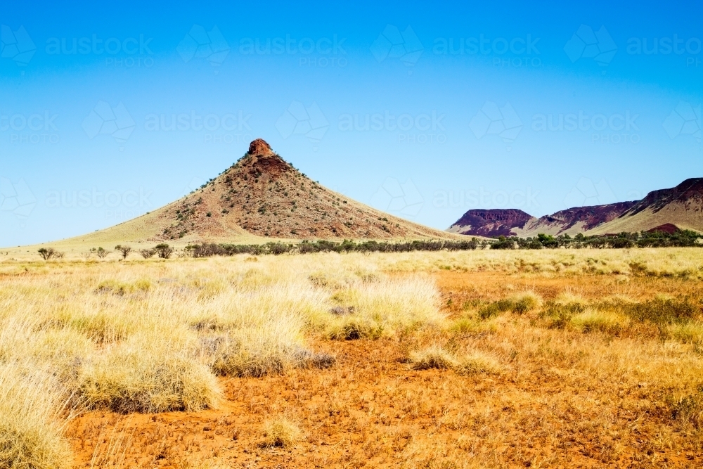 Hill rising from spinifex plains - Australian Stock Image
