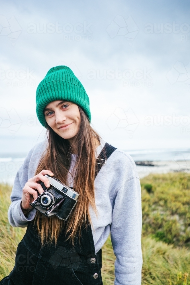 Hip young girl with old school film camera by the sea - Australian Stock Image