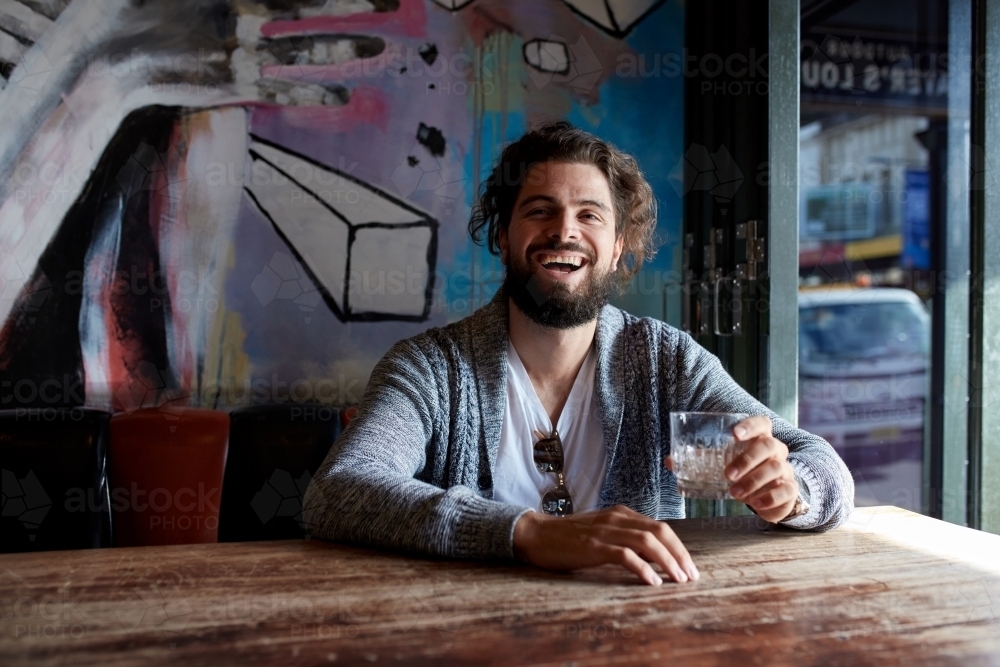 Hipster man enjoying drinking a beer at pub - Australian Stock Image