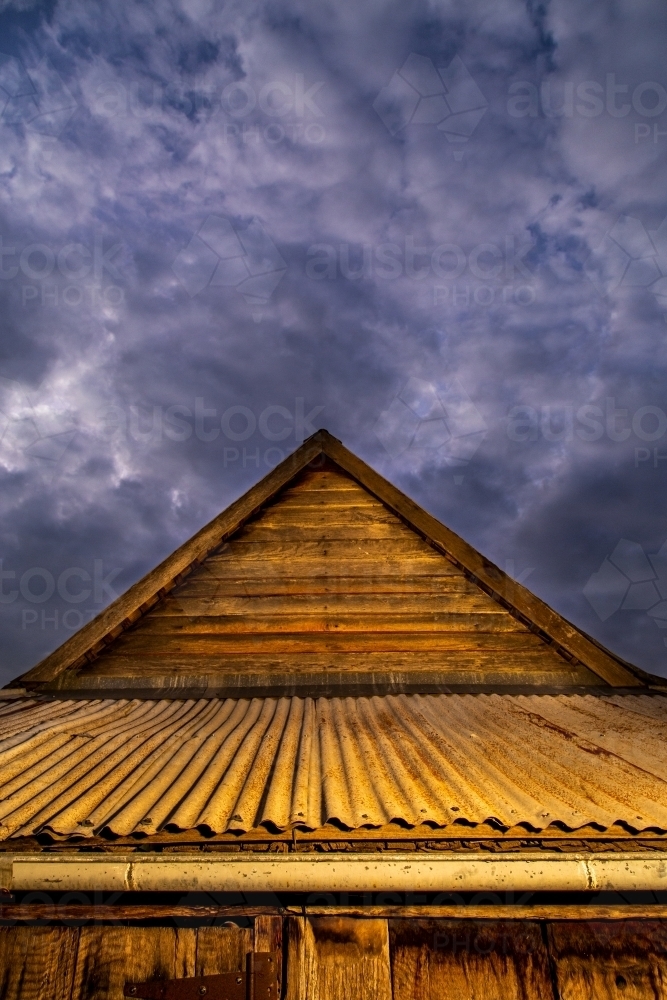 Historic wooden farm building under a stormy sky. - Australian Stock Image