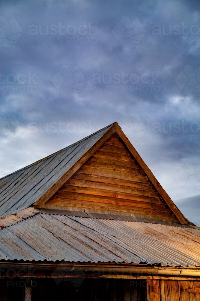 Historic wooden farm building under a stormy sky. - Australian Stock Image