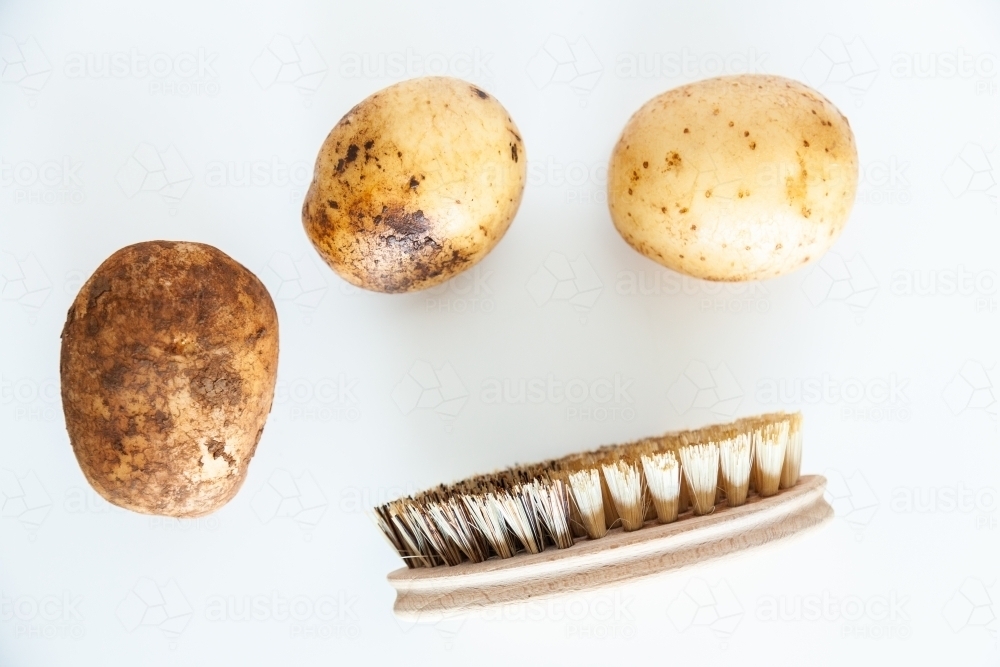 Home grown potatoes and eco-friendly vegetable brush to clean them with - Australian Stock Image