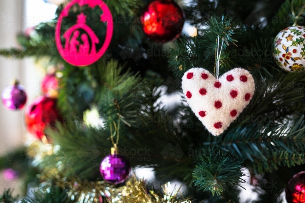 Homemade heart christmas decoration hanging on a christmas tree with other ornaments - Australian Stock Image