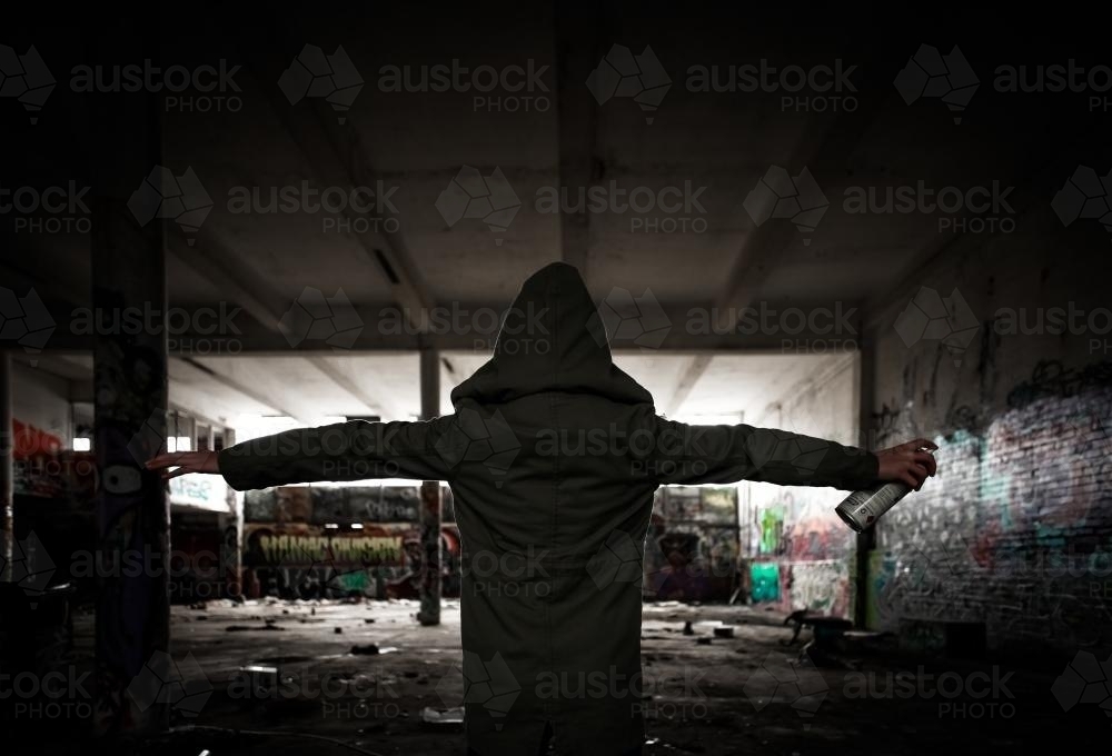 Hooded girl holding spray paint in a pose of defiance - Australian Stock Image