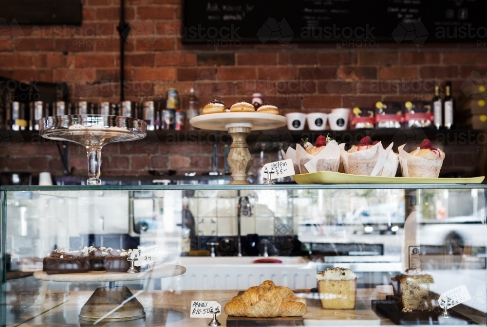 Horizontal cake display case in cafe with rustic wall behind - Australian Stock Image