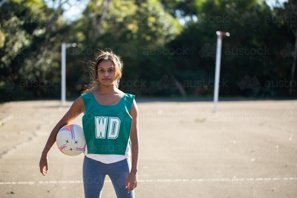 horizontal outdoor shot of a Indian woman in sports wear holding a ball - Australian Stock Image