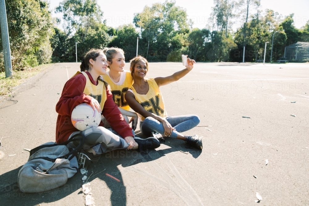 horizontal photo of three young women taking a selfie while sitting on the ground on a sunny day - Australian Stock Image