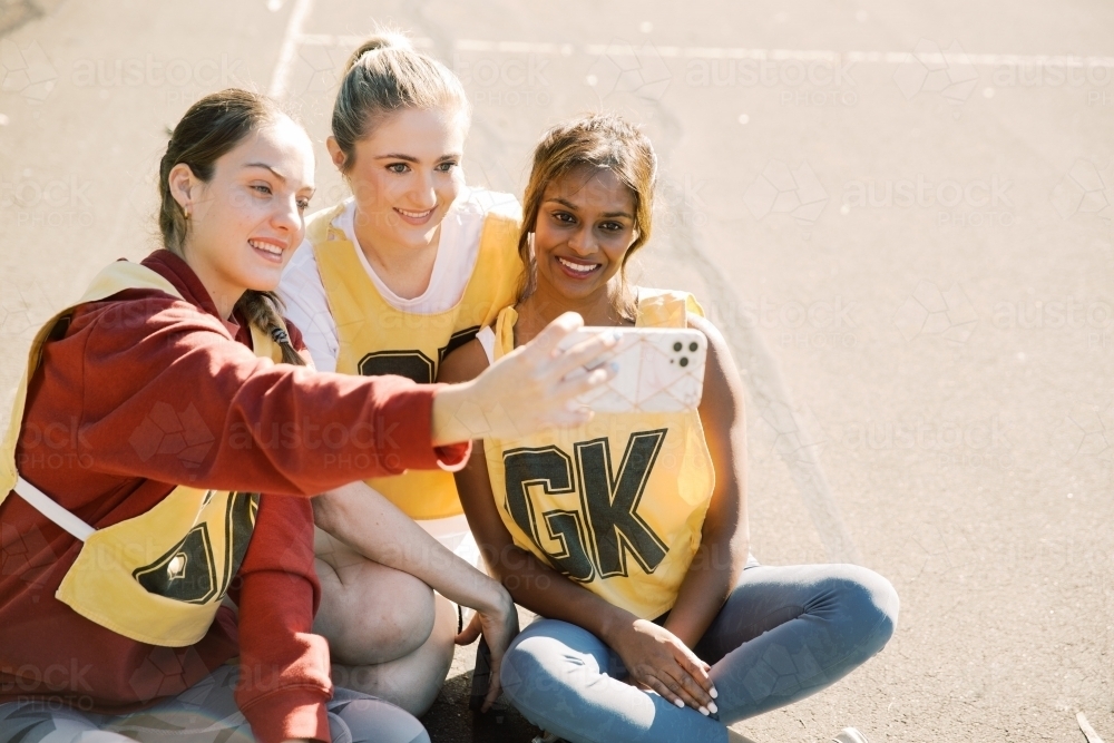 horizontal photo of three young women taking a selfie while sitting on the ground on a sunny day - Australian Stock Image