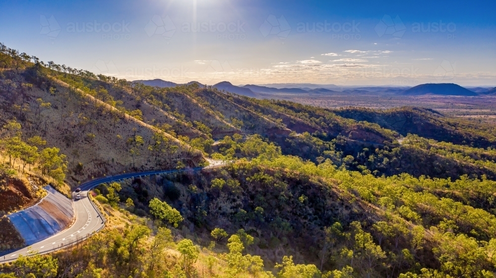 Horizontal photo of winding road in Mount Morgan with a steep road side with wild flowers and plants - Australian Stock Image