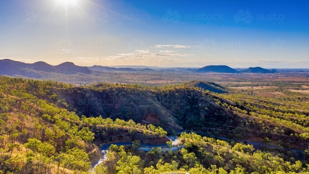 Horizontal photo of winding road in Mount Morgan with a steep road side with wild flowers and plants - Australian Stock Image