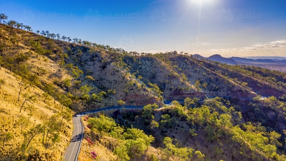 Horizontal photo of winding road in Mount Morgan with a steep road side with wild flowers and plants - Australian Stock Image