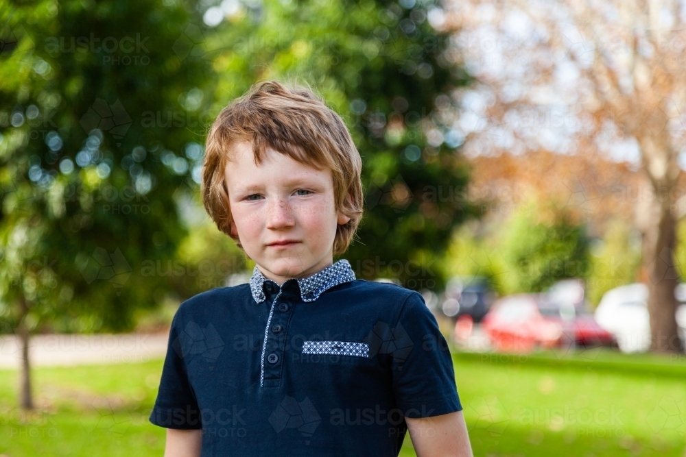 Horizontal portrait of unsure little boy with autism, at park outside - Australian Stock Image