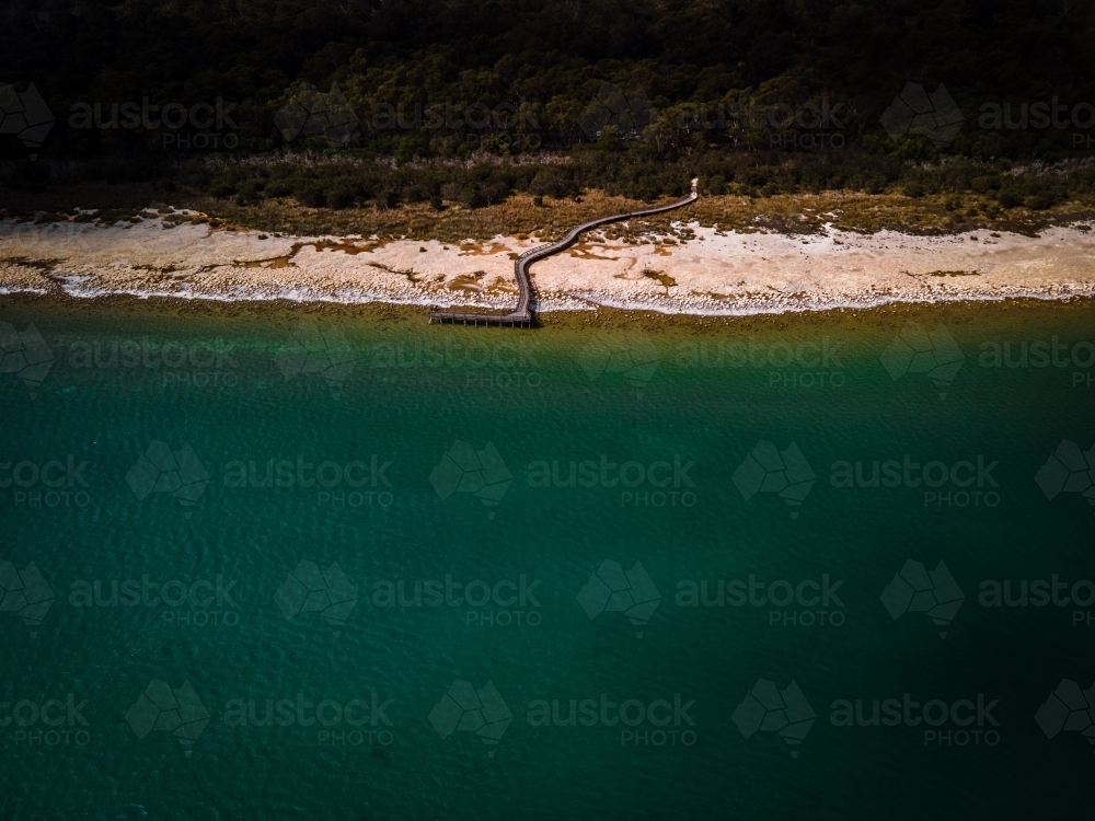 horizontal shot of a beach walkway with bushes, trees and waves on a sunny day - Australian Stock Image