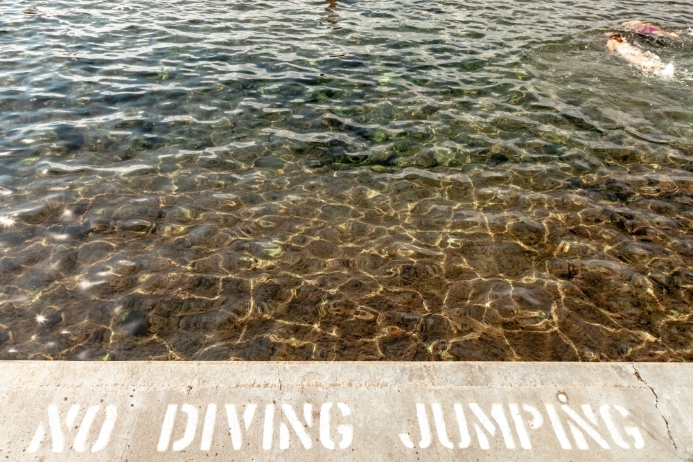horizontal shot of a beach with a no diving and no jumping sign - Australian Stock Image
