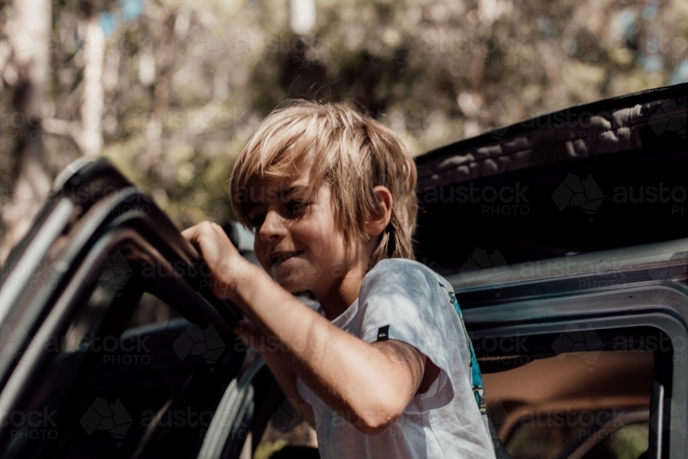 Horizontal shot of a boy leaning on the car door - Australian Stock Image