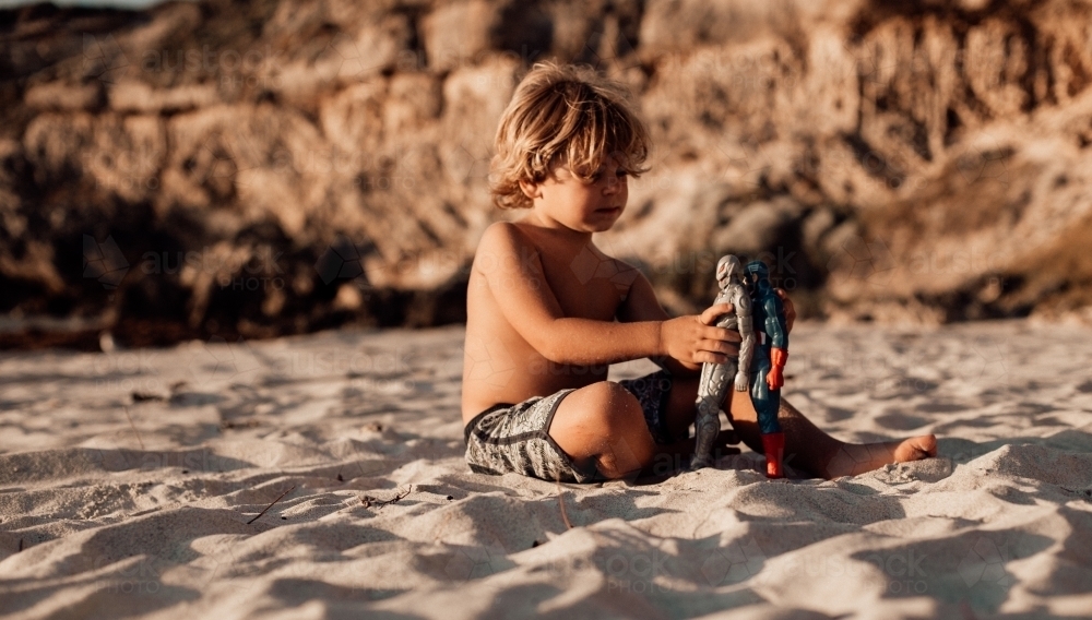 Horizontal shot of a boy playing with his toys in the sand - Australian Stock Image
