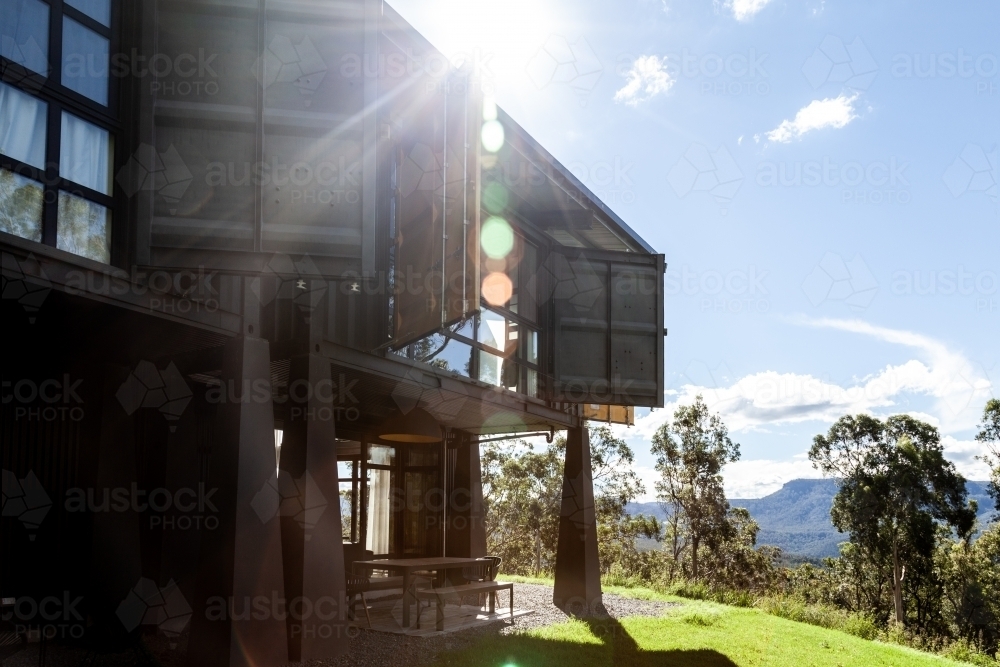 horizontal shot of a house with open windows and grassy lawn with trees on a sunny day - Australian Stock Image