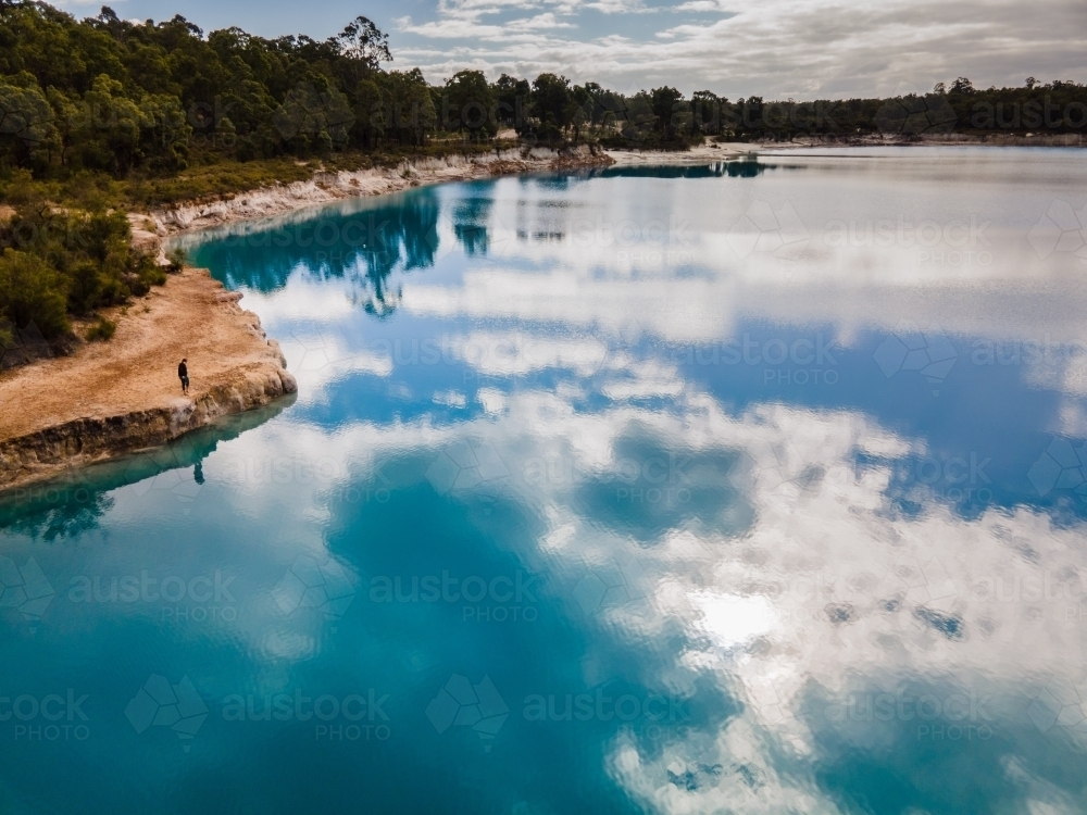 horizontal shot of a lake with sky reflection surrounded  by green trees - Australian Stock Image