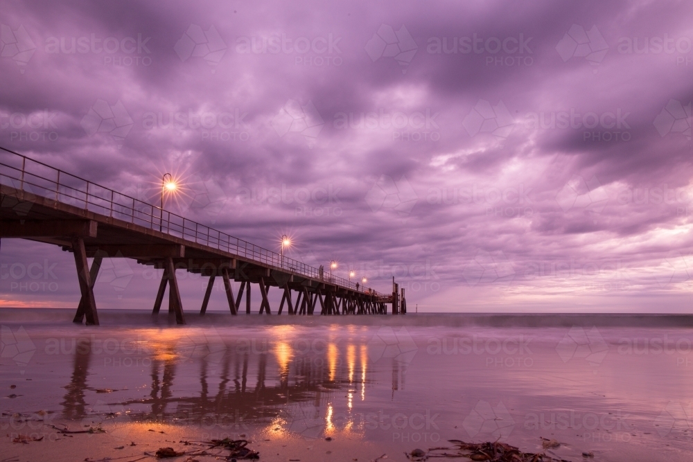 Horizontal shot of a long wharf on the beach at night time - Australian Stock Image