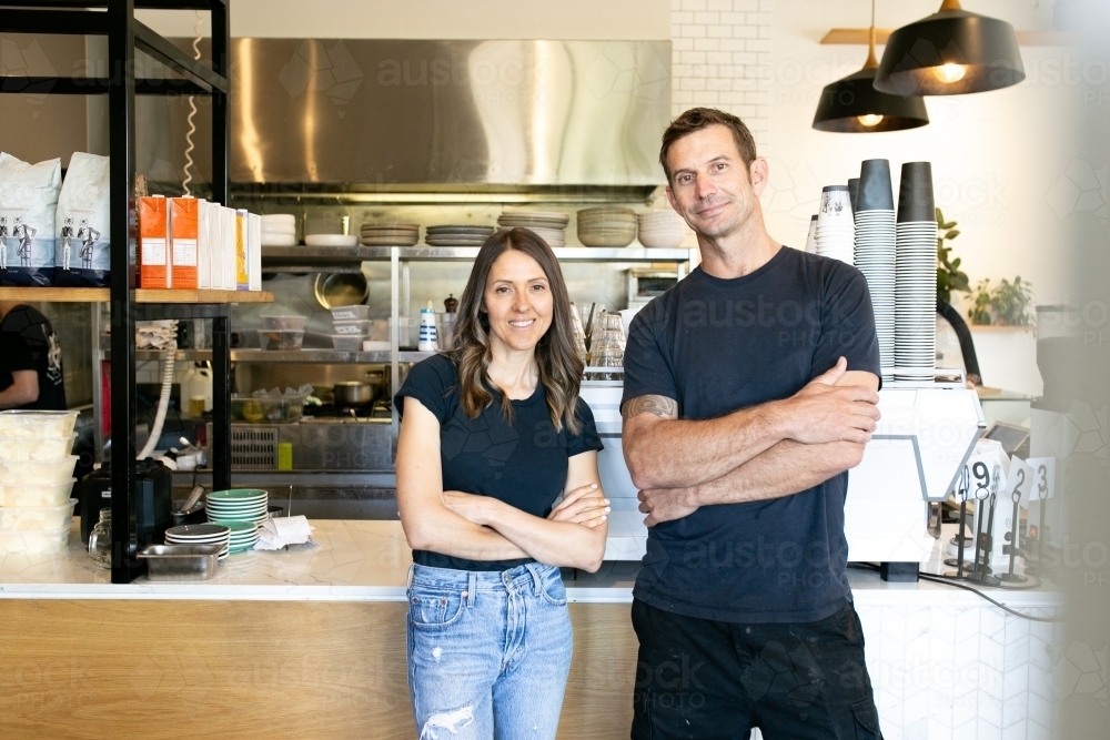 horizontal shot of a man and a woman both with arms crossed on chest  and wearing black shirt - Australian Stock Image
