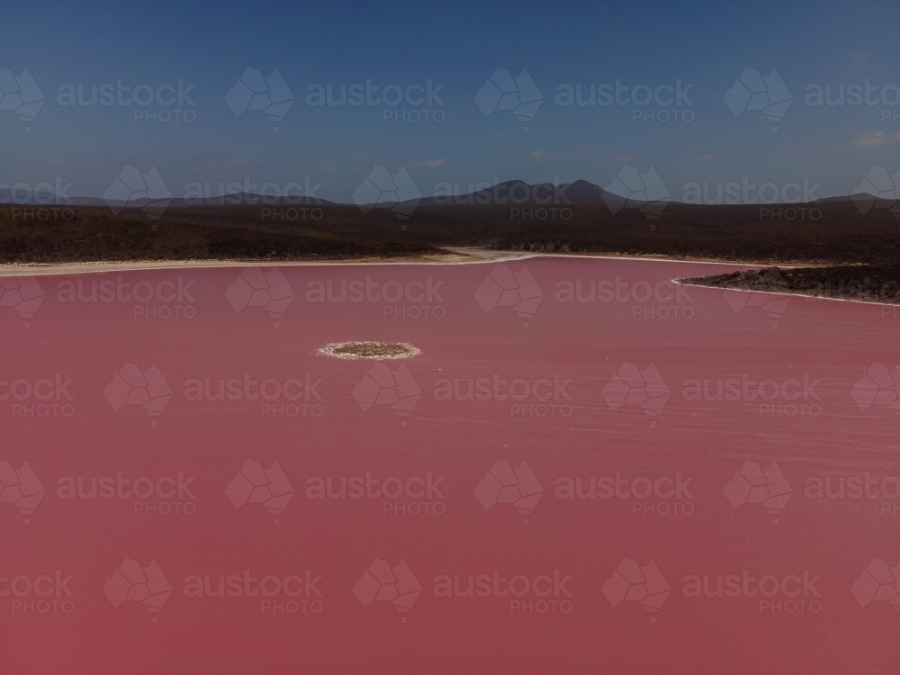 horizontal shot of a pink salt lake with mountains and clear sky - Australian Stock Image