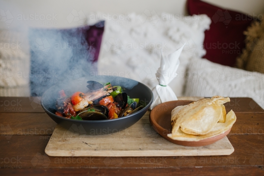 Horizontal shot of a plate of large thin pita bread and a hot bowl of prawn with mussels - Australian Stock Image