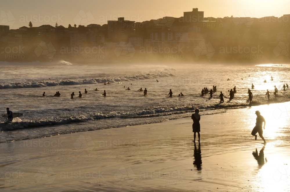 horizontal shot of a remote beach with people. mountains, rocks and waves with sunset - Australian Stock Image
