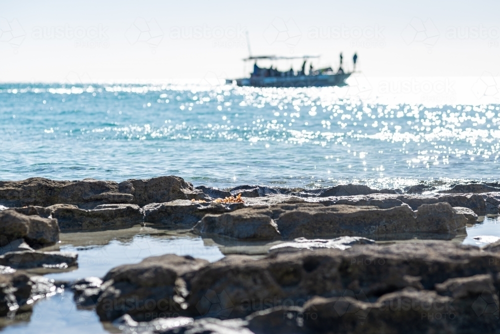 Horizontal shot of a rocky foreground boat in background - Australian Stock Image