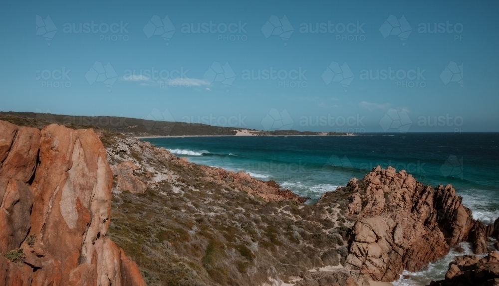 Horizontal shot of a rocky seashore under a blue sky - Australian Stock Image