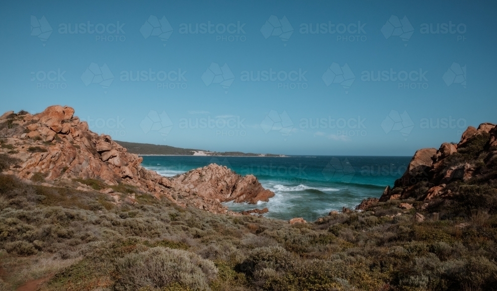 Horizontal shot of a rocky seashore under a blue sky - Australian Stock Image