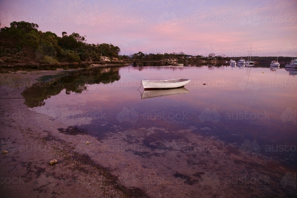 small boat on beach at low tide - Australian Stock Image