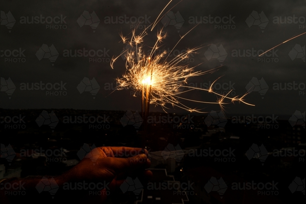 Horizontal shot of a sparkler with a dark background - Australian Stock Image
