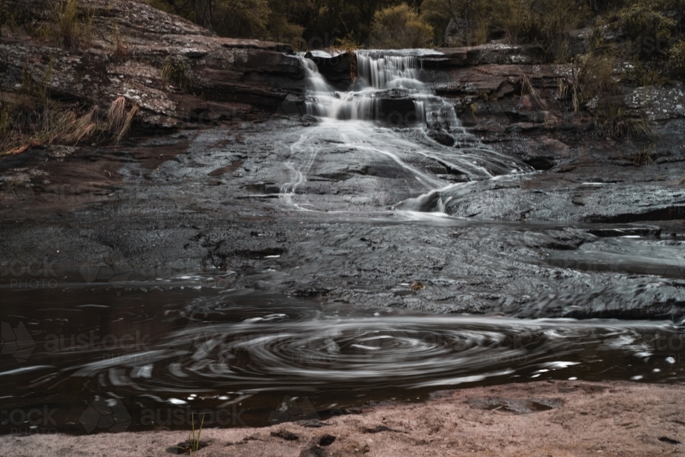 Horizontal shot of a swirling water coming from the waterfall - Australian Stock Image