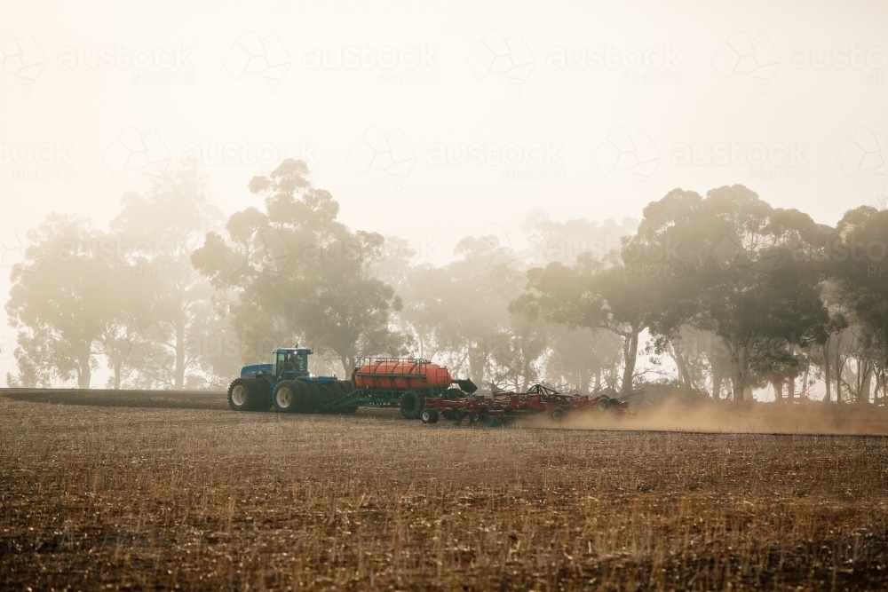 Horizontal shot of a tractor cultivating the soil in the field. - Australian Stock Image