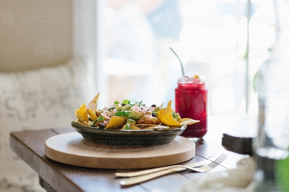 Horizontal shot of a vegetable nachos and red juice on a wooden table - Australian Stock Image