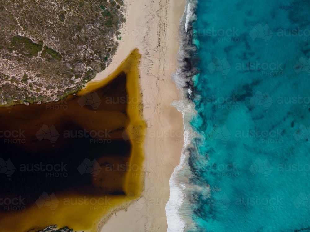 horizontal shot of a white sand beach with bushes, and waves on a sunny day - Australian Stock Image