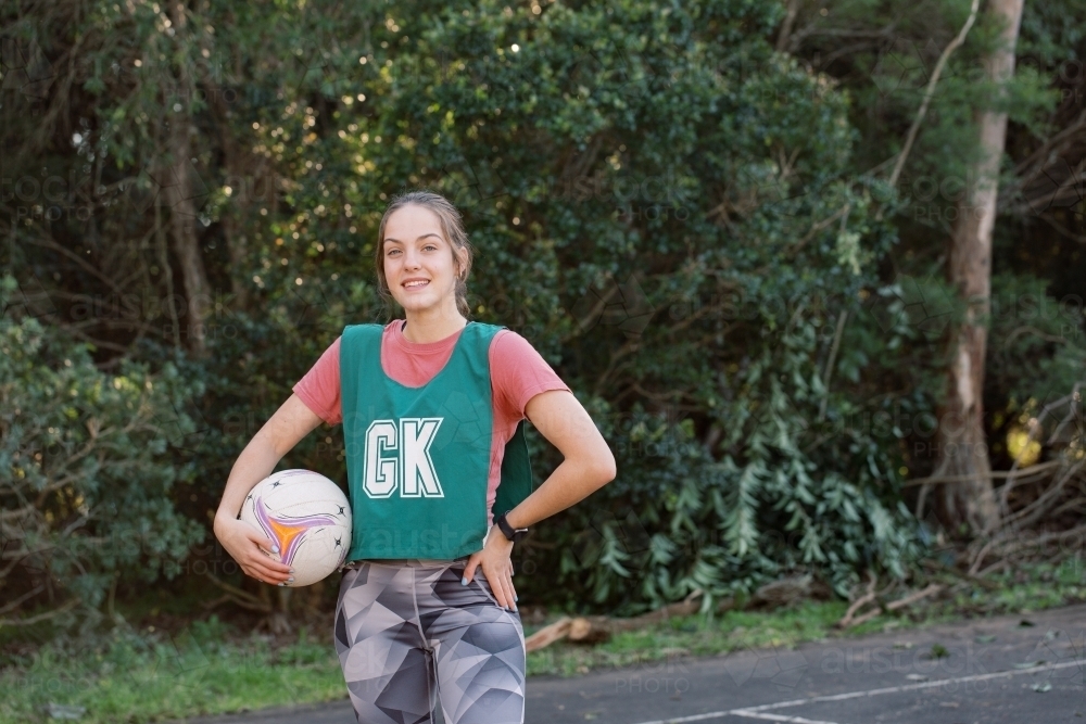 horizontal shot of a young woman in sports wear holding a net ball with other hand against her hips - Australian Stock Image