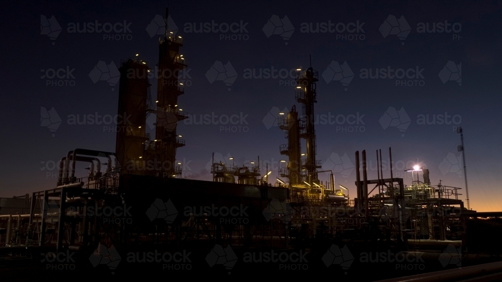 Horizontal shot of an industrial plant approaching sunrise or after sunset - Australian Stock Image