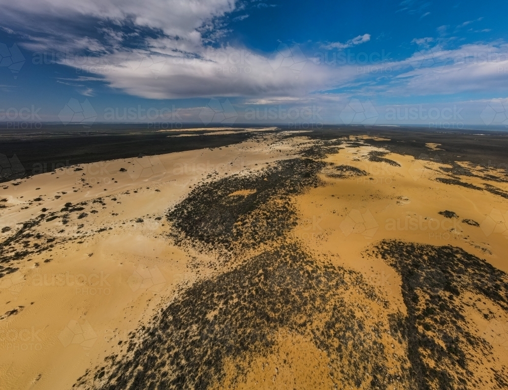horizontal shot of an outback near the ocean with green bushes on a sunny day with cloudy skies - Australian Stock Image