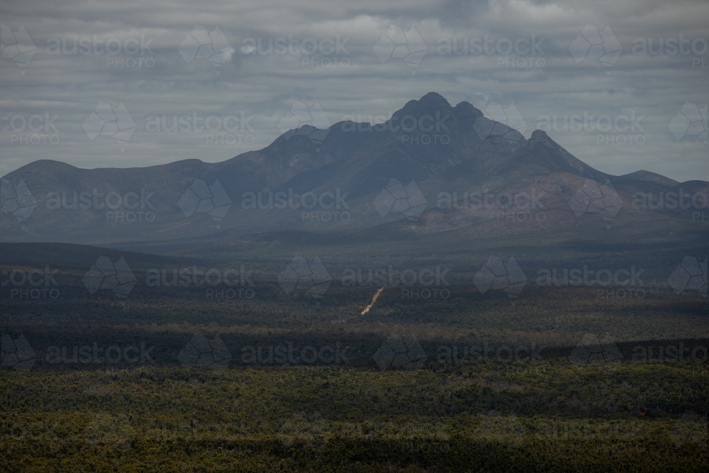 horizontal shot of an outback with grass, bushes, and mountain on a gloomy day - Australian Stock Image
