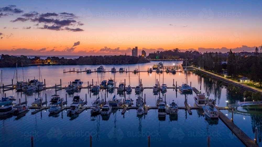 Horizontal shot of boats all lined up at marina at sunset - Australian Stock Image
