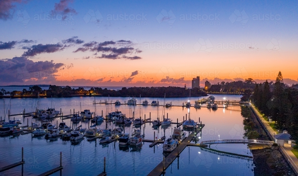 Horizontal shot of boats all lined up at marina at sunset - Australian Stock Image