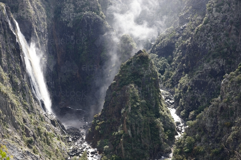 Horizontal shot of foggy ravine and waterfall from cliff - Australian Stock Image