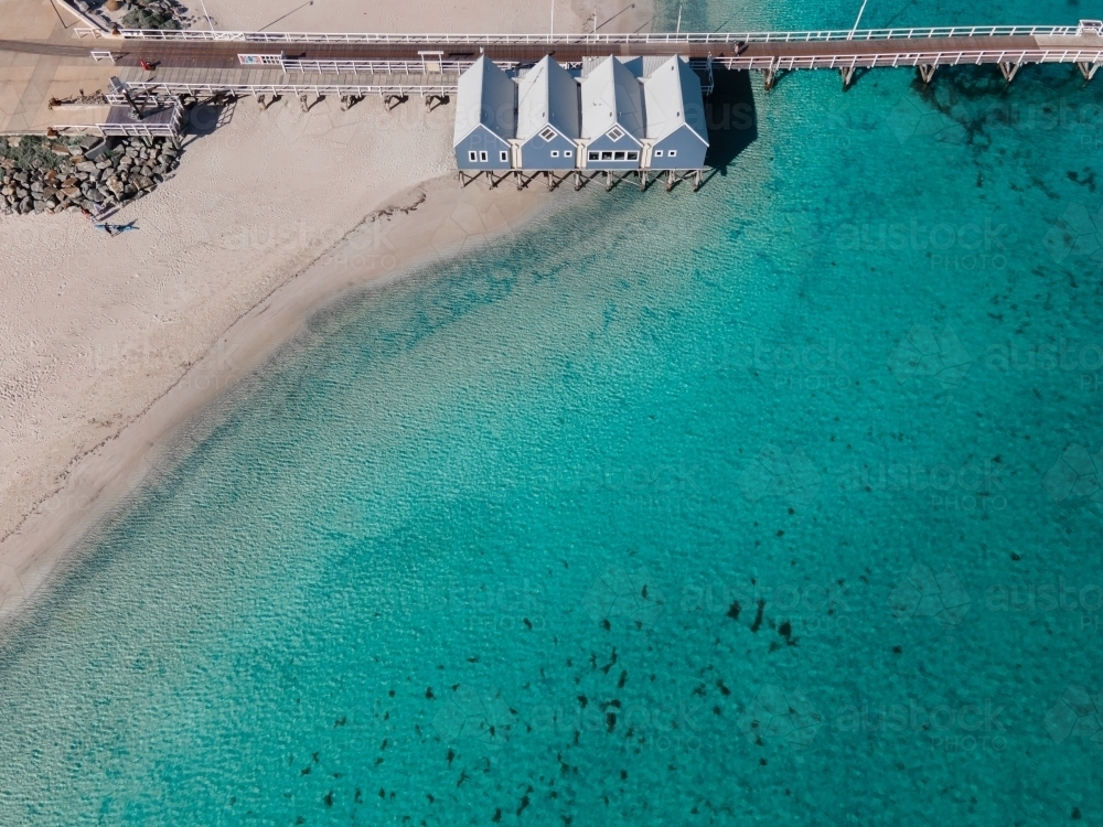 horizontal shot of four beach buildings with walkway with clear blue and green waters and white sand - Australian Stock Image