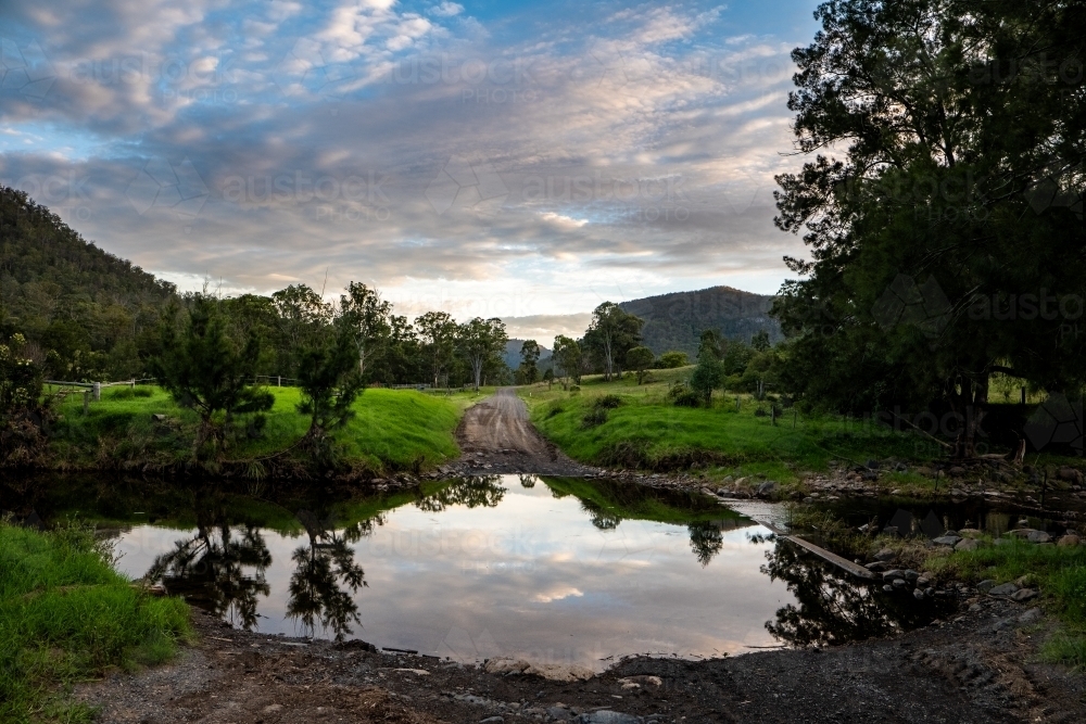 Horizontal shot of green trees near a lake under a cloudy blue sky - Australian Stock Image