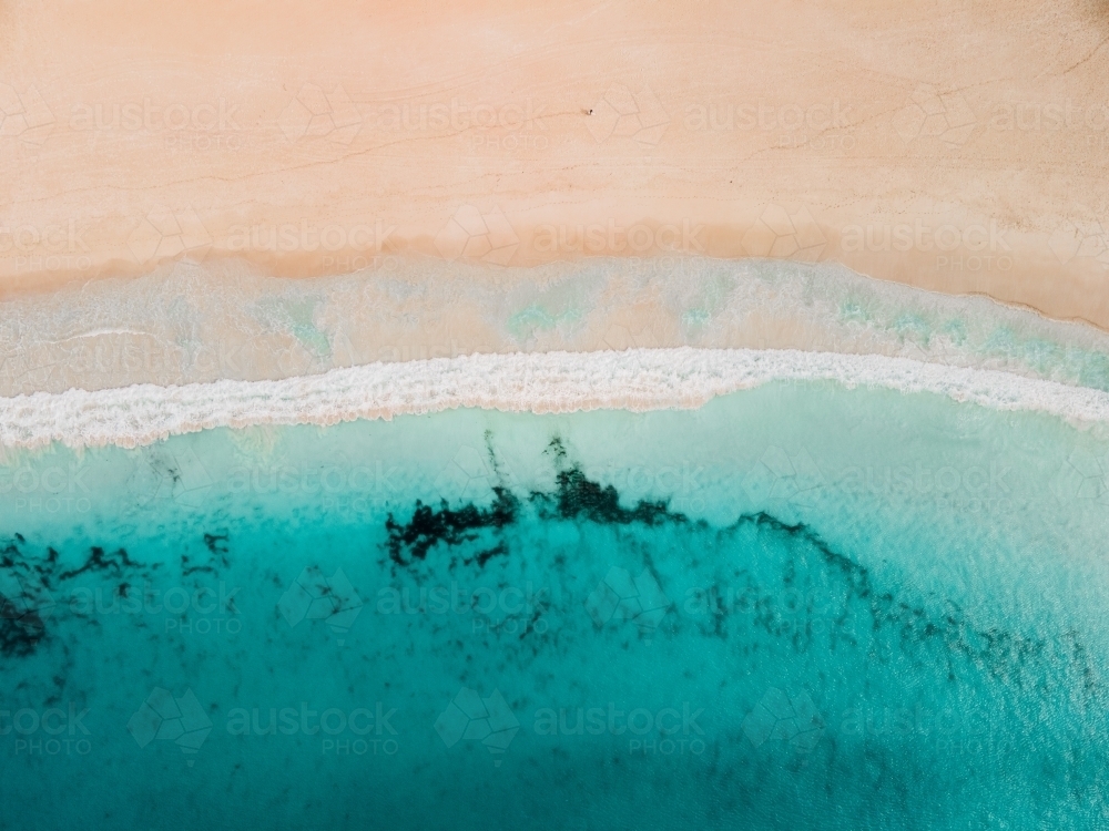 Horizontal shot of ocean waves on empty sand beach - Australian Stock Image