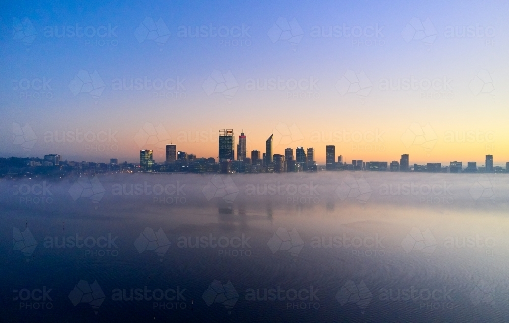 Perth skyline at dawn with fog on the Swan River surrounding the CBD - Australian Stock Image
