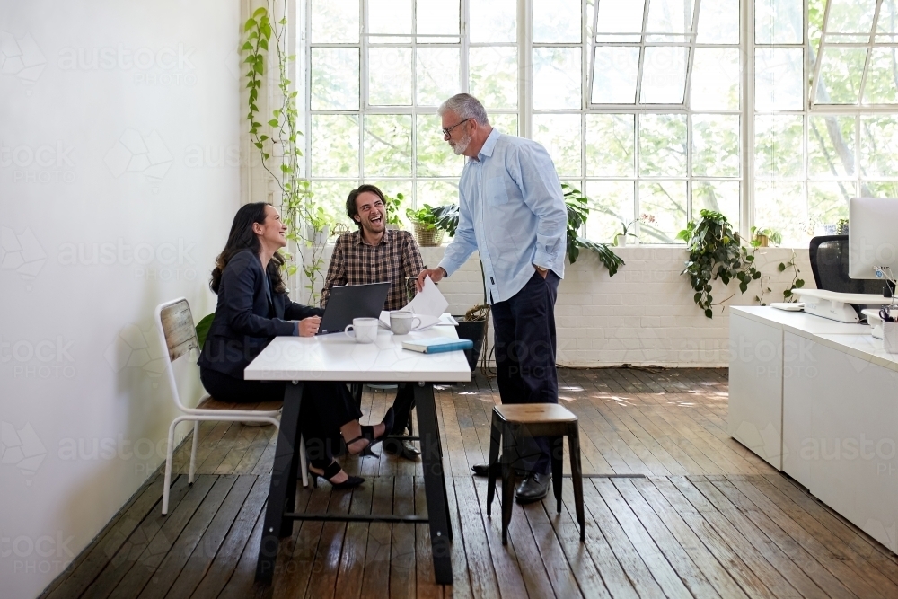 Horizontal shot of three people having a meeting inside a room painted mostly in white - Australian Stock Image