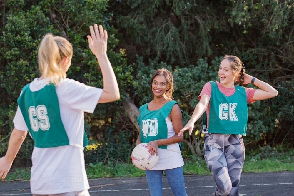 horizontal shot of three smiling young women in sports wear about to give high five to each other - Australian Stock Image